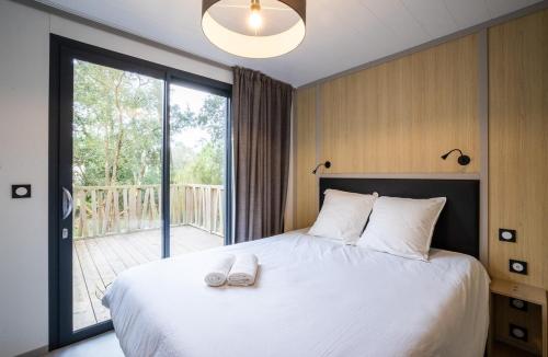 une chambre avec un lit avec deux serviettes dessus dans l'établissement Green Resort Chalet with Clim & Pool, à Ondres