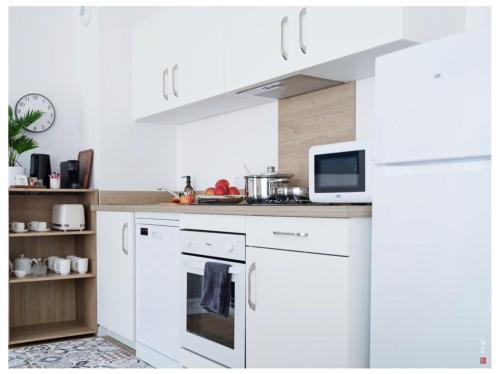 Il comprend une cuisine blanche équipée d'une cuisinière et d'un four micro-ondes. dans l'établissement Appart entre Paris et Disney - inclus Park et Wifi, à Champs-sur-Marne