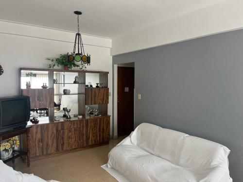 a living room with a white couch and a tv at Departamento frente al mar tres dormitorios in Mar del Plata