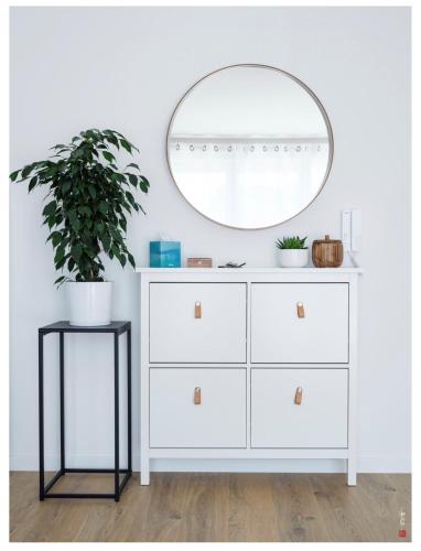 - une commode blanche avec un miroir et une plante dans l'établissement Appart entre Paris et Disney - inclus Park et Wifi, à Champs-sur-Marne