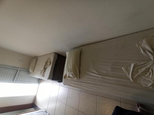 ein Bett mit zwei Kissen darauf in einem Zimmer in der Unterkunft Pousada raios de sol indaia in Bertioga