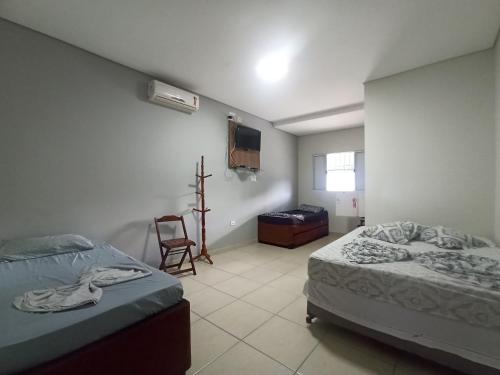 ein Schlafzimmer mit zwei Betten und einem Fernseher an der Wand in der Unterkunft Pousada raios de sol indaia in Bertioga