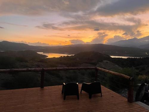 two chairs sitting on a deck watching the sunset at Casa del Plata Lodge in Potrerillos