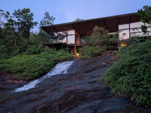 a house in the woods with a waterfall at Kurunduketiya Private Rainforest Resort in Kalawana