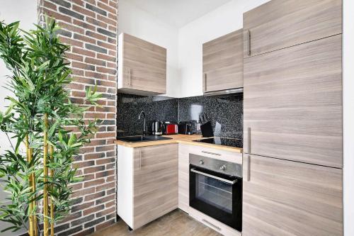 une cuisine avec des placards en bois et un mur en briques dans l'établissement Superb apartment - 1BR 4P - Gare Montparnasse, à Paris
