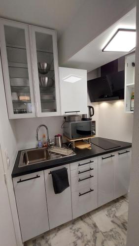 une petite cuisine avec des armoires blanches et un évier dans l'établissement Studio F1 avec jardin, proche du Palais des festivals et des plages, à Cannes