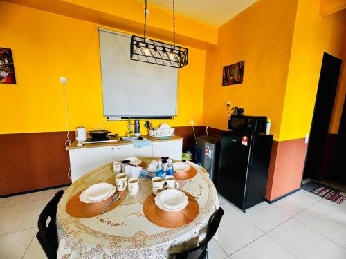a kitchen with a table and a yellow wall at Deluxe Suites with Infinity Pool, Kids' Pool & Sea in Jelutong