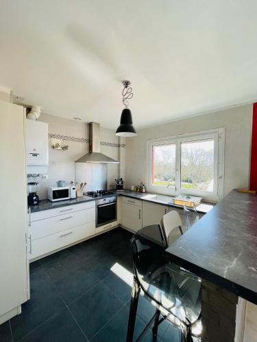 une cuisine avec des armoires blanches et un comptoir noir dans l'établissement Chambre chez l'habitant ou Homestay dans le quartier de BONHOURE, à Toulouse