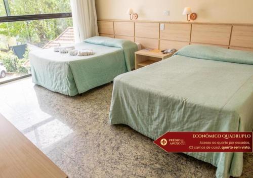 a hotel room with two beds and a window at Hotel Castelo Nacional Inn Campos do Jordão in Campos do Jordão