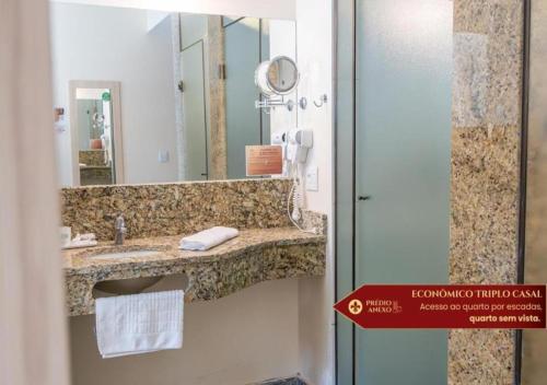 a bathroom with a sink and a mirror at Hotel Castelo Nacional Inn Campos do Jordão in Campos do Jordão