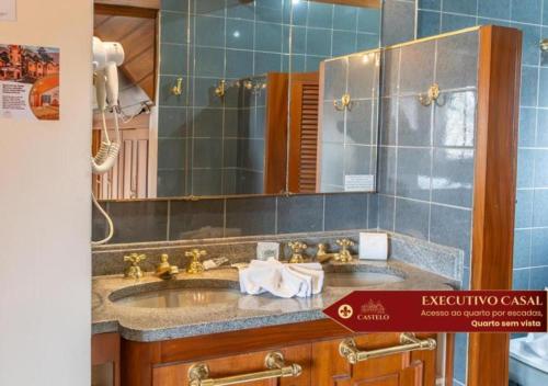 a bathroom with a sink and a mirror at Hotel Castelo Nacional Inn Campos do Jordão in Campos do Jordão