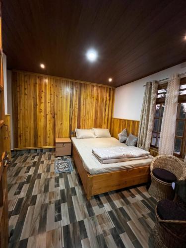 une chambre avec un lit dans une pièce aux murs en bois dans l'établissement Payun Homestays, à Darjeeling