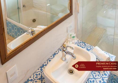 a bathroom with a sink and a mirror at Hotel Castelo Nacional Inn Campos do Jordão in Campos do Jordão