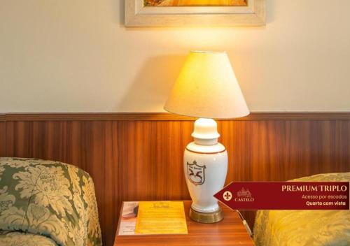 a lamp sitting on a table next to a chair at Hotel Castelo Nacional Inn Campos do Jordão in Campos do Jordão