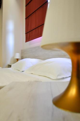 a bedroom with two beds with white pillows and a lamp at Boutique Hostel Livia in Metković
