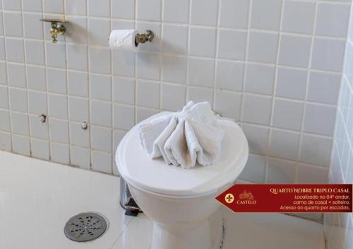 a bathroom with a toilet with a towel on it at Hotel Castelo Nacional Inn Campos do Jordão in Campos do Jordão
