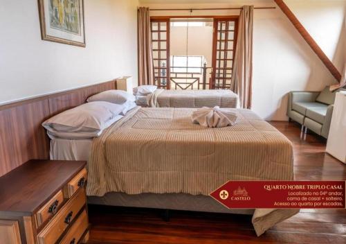 a room with two beds and a table and a chair at Hotel Castelo Nacional Inn Campos do Jordão in Campos do Jordão