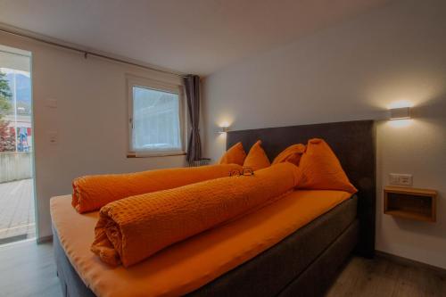 a bed with an orange blanket on top of it at Ristorante Pensione Chalet Stazione in Poschiavo