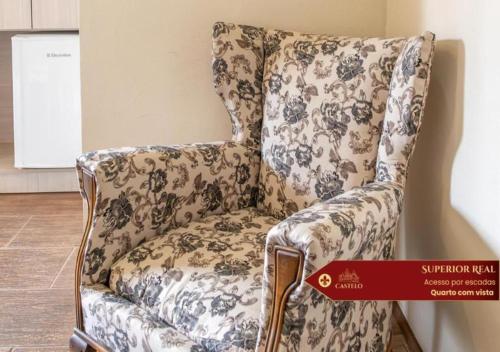 a chair in a room with a flowery pattern at Hotel Castelo Nacional Inn Campos do Jordão in Campos do Jordão