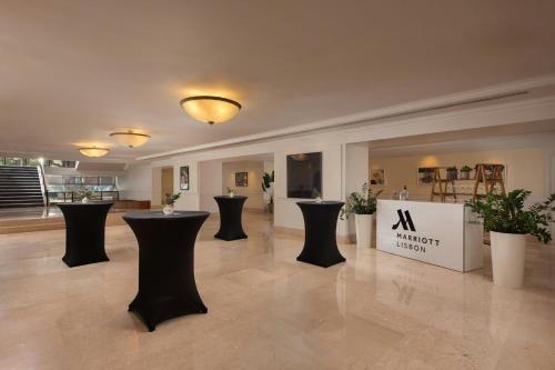 a large room with black tables and potted plants at Lisbon Marriott Hotel in Lisbon