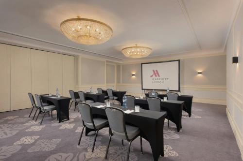 a conference room with tables and chairs and a screen at Lisbon Marriott Hotel in Lisbon