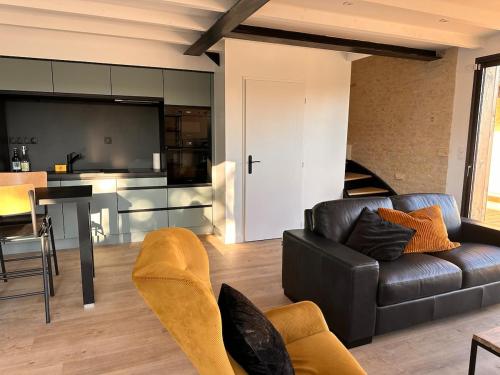 un salon avec un canapé en cuir et une table dans l'établissement La Grange d 'Arçais-sans linge de maison, à Arçais