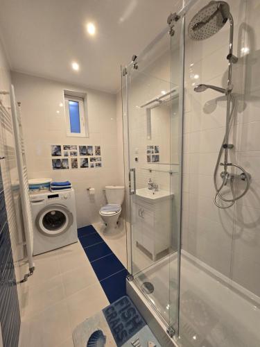 a bathroom with a shower and a washing machine at TROPIC-APARTAMENTY in Hel