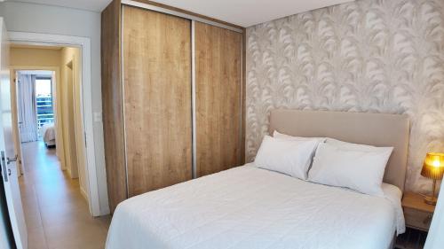 a bedroom with a white bed and a wooden wall at HOUZE - Stay & Residences by AVA in Asuncion
