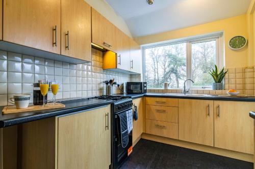 a kitchen with wooden cabinets and a black stove top oven at University View-Off-Street Parking-Sleeps 8-Fast WiFi in Nottingham