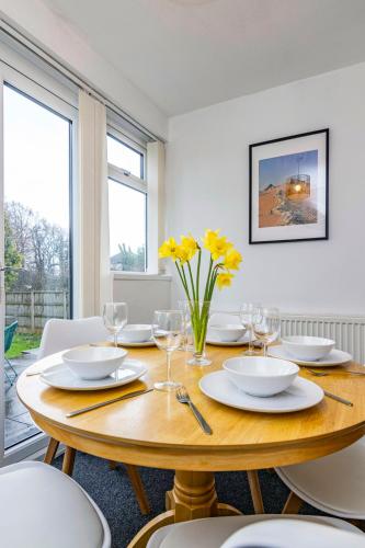a dining room with a wooden table with yellow flowers at University View-Off-Street Parking-Sleeps 8-Fast WiFi in Nottingham