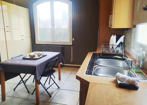 eine kleine Küche mit einem Waschbecken und einem Tisch in der Unterkunft Chambre Cosy bien équipée proche RER aux Portes de Paris in Stains