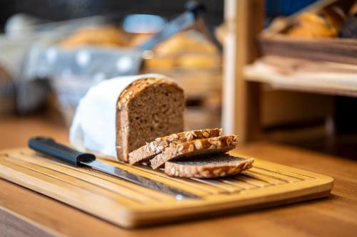 a loaf of bread on a cutting board with a knife at Dream Factory by Hotel Bergheim in Bergheim
