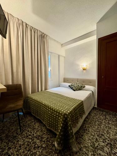 a bedroom with a bed and a chair and a window at Hotel BH Los Ángeles in Benidorm