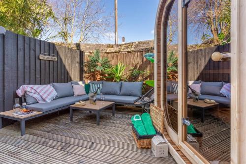 a patio with couches and tables and a fence at 5 min walk to beach with parking and private sauna in Falmouth