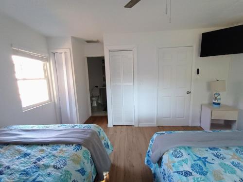 a bedroom with two beds and a window and a door at St Pete heated pool hot tub 5 min to the beach in St Petersburg