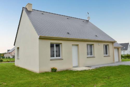 a white house with a gray roof at Maison de charme à Saint-Laurent-sur-Mer, vue sur mer et jardin in Saint-Laurent-sur-Mer