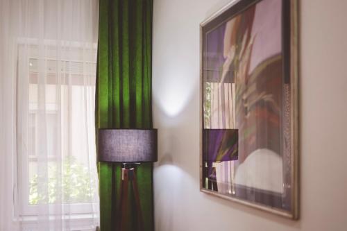 a green wall with a picture and a lamp next to a window at AMMOTTI Hotel in Ohrid