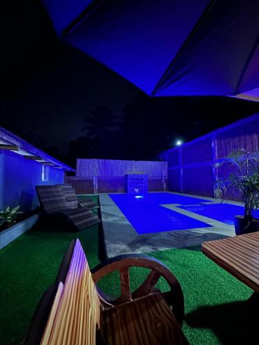 a backyard with a pool at night with purple lights at Main Kubo, La Ahoy RestHouse and Resort in San Jose