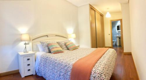 a bedroom with a bed and a night stand with a lamp at Apartamento Europa Jardin in Oviedo