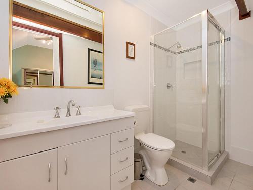 a white bathroom with a shower and a toilet at Ainslie Manor Guest House in Redcliffe