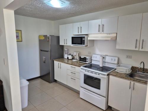 a kitchen with white appliances and white cabinets at Family getaway, pool, beach and surf in Jacó