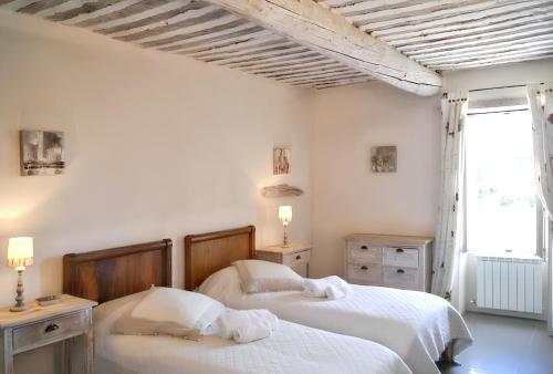 two beds in a bedroom with white walls and a window at Villa spacieuse à Oppède avec piscine et vue imprenable in Oppède