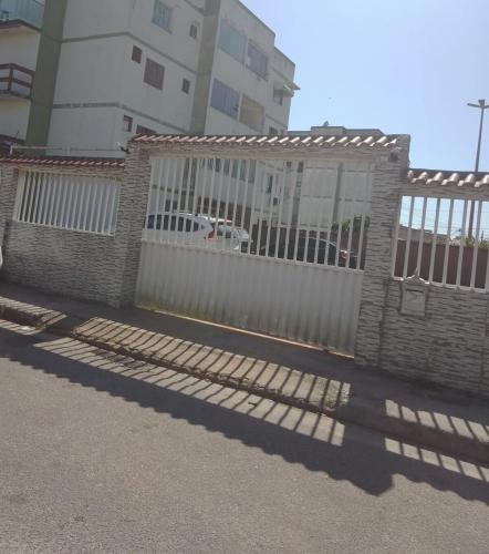 a fence with a white gate in front of a building at Arbricot in Rio das Ostras