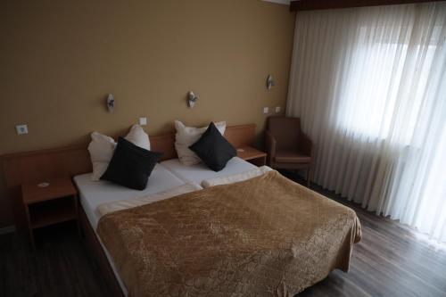 a hotel room with a bed with black pillows at Hotel Hohe Wart in Herbrechtingen