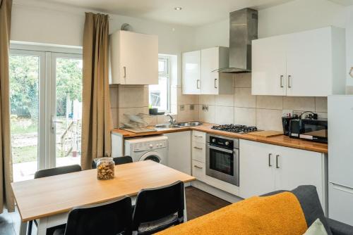 a kitchen with white cabinets and a wooden table at Lovely 3 bed house in Feltham in Feltham