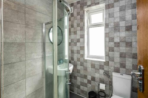 a bathroom with a shower and a toilet and a window at Lovely 3 bed house in Feltham in Feltham
