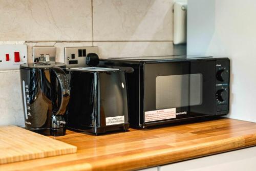 two microwaves sitting on top of a kitchen counter at Lovely 3 bed house in Feltham in Feltham