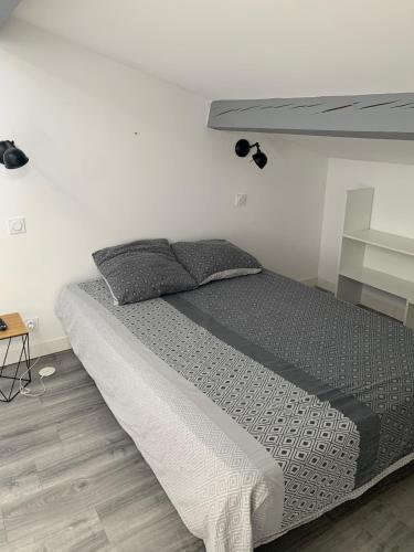 Ce lit se trouve dans une chambre dotée d'un mur blanc. dans l'établissement Studio Tuco, à Mont-de-Marsan