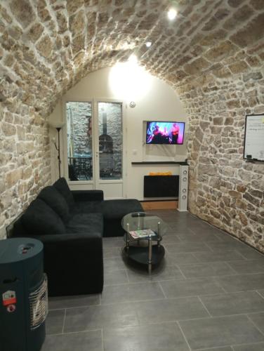 un salon avec un canapé noir et un mur en pierre dans l'établissement Appartement de charme, à Cournonterral