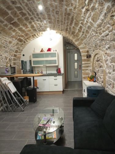 - un salon avec une table en verre et un mur en pierre dans l'établissement Appartement de charme, à Cournonterral
